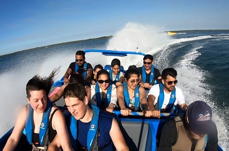 GC Jet boat roaring through the Gold Coast waterways with the city skyline in the backdrop