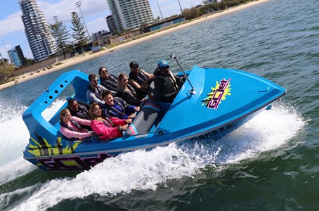 GC Jet boat roaring through the Gold Coast waterways with the city skyline in the backdrop